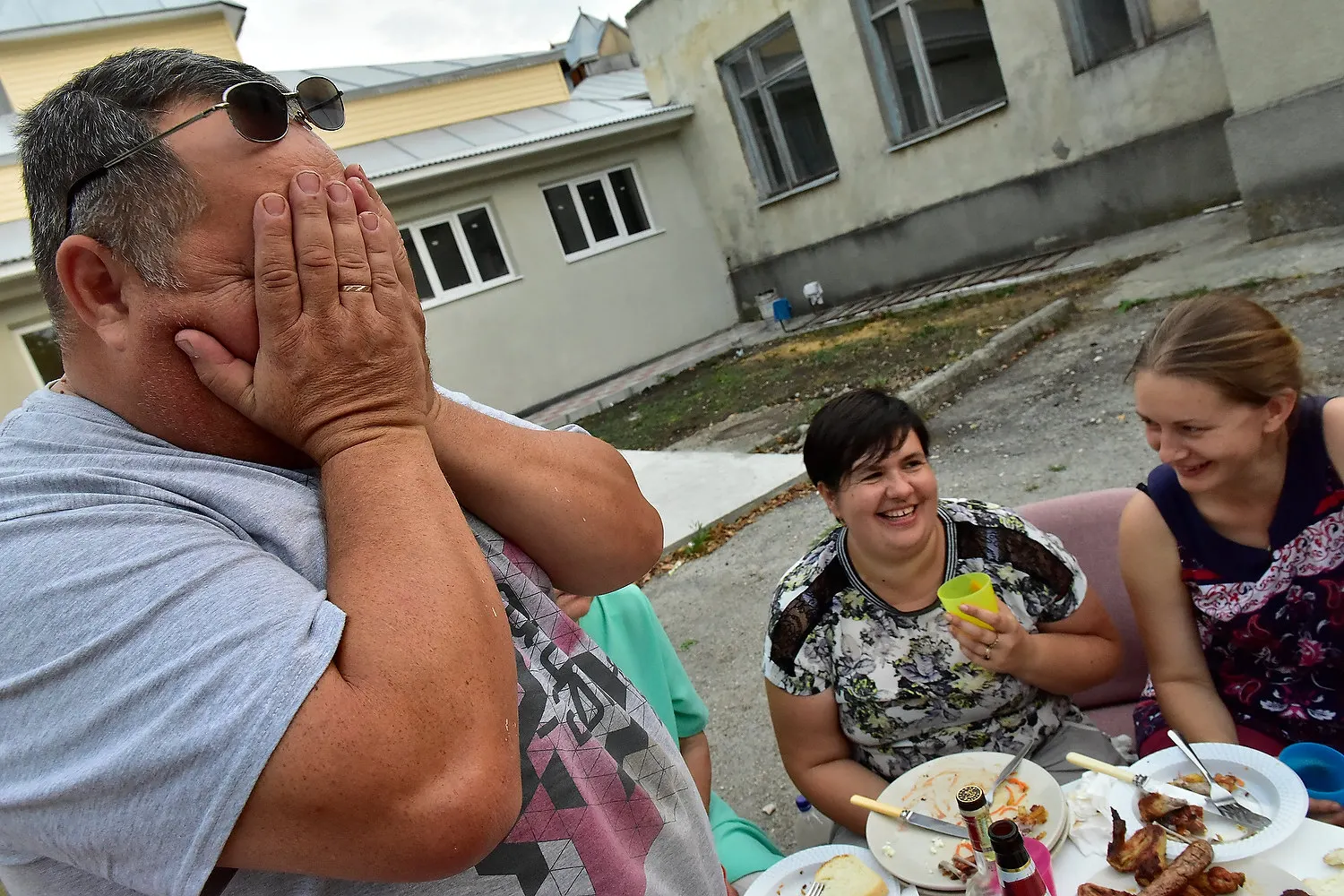 Vârstnici râzând la o masă în aer liber la Casa Phoenix